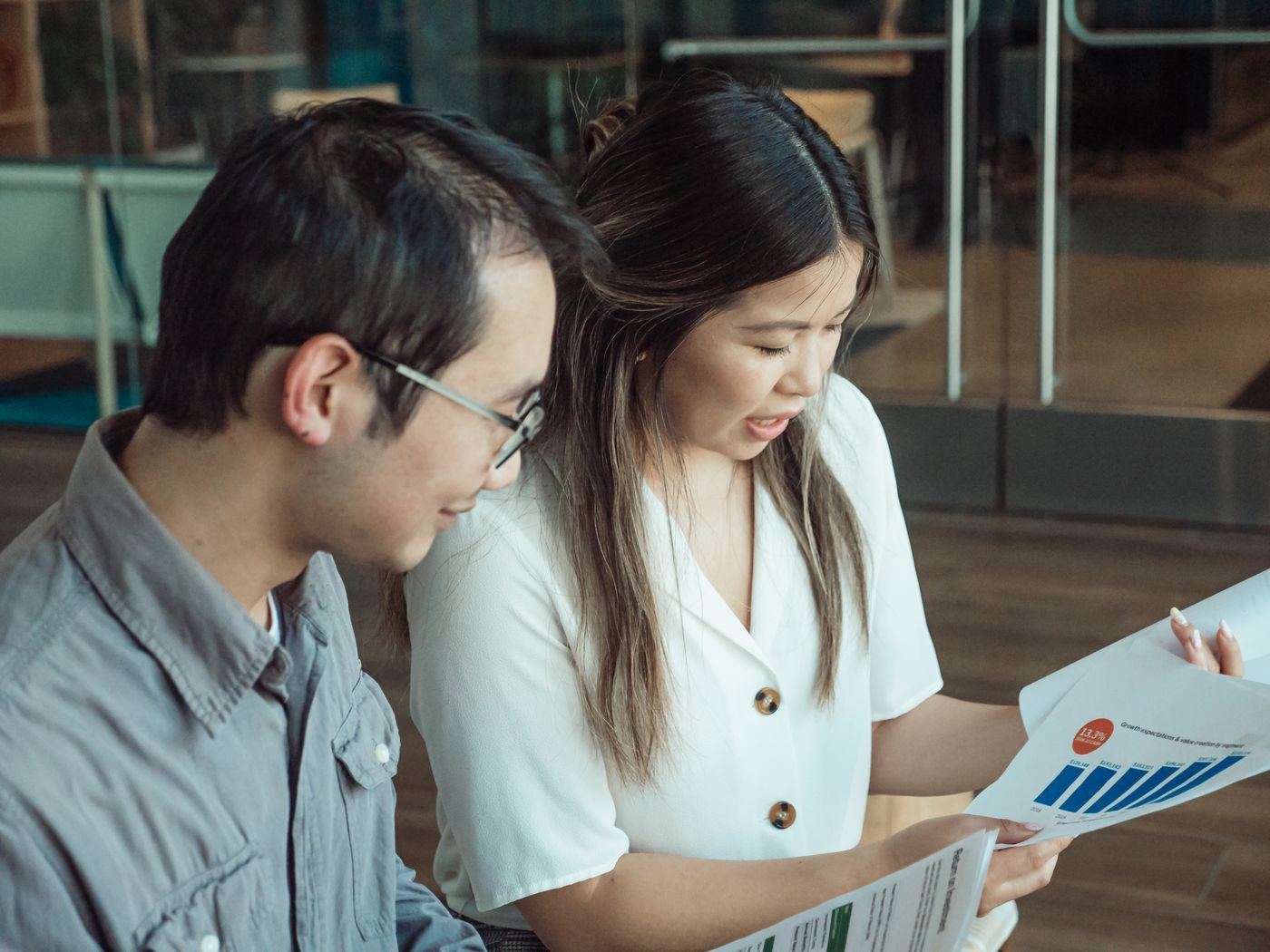 Two finance colleagues reviewing printed figures